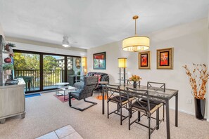 Un salon moderne avec une table à manger, des chaises et un canapé. Il y a un balcon avec vue sur l’extérieur.