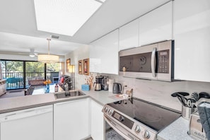 A modern kitchen with white cabinets, a built-in microwave, a stove, and a dishwasher.