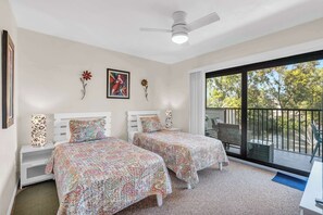 A bedroom with two beds, a ceiling fan, a large window, and a view of the outdoors. - H-247 - Second Floor With Lake and Fountain View (Naples)