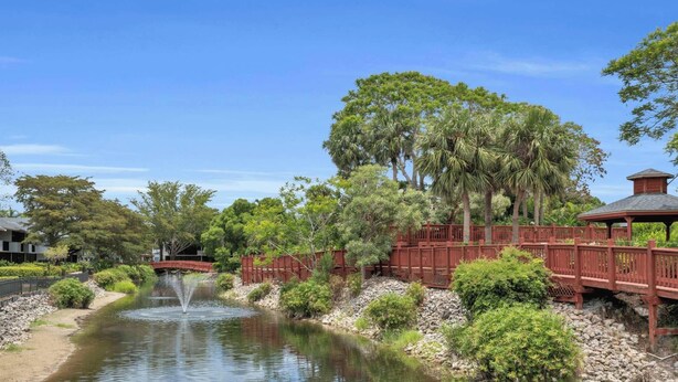 A tranquil garden with a pond, a wooden bridge, and a gazebo. - H-247 - Second Floor With Lake and Fountain View (Naples)