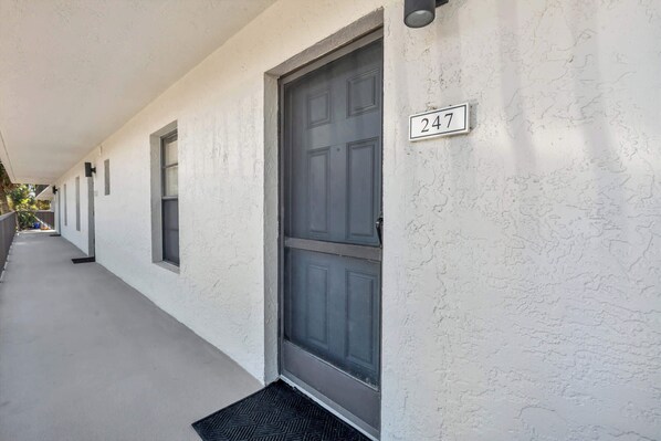 A building exterior with a number 247 sign, a covered walkway, and a door.