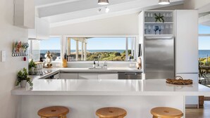 A modern kitchen with a large island, stainless steel appliances, and a view of the ocean. - Beachfront Retreat Su (Mount Maunganui)