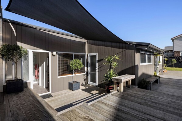 A modern building with a covered patio area, wooden deck, and potted plants.