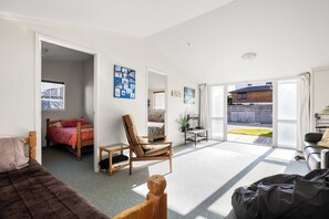 A bedroom with a bed, a chair, a desk, and a view of the outside.