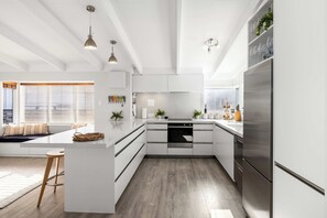 A modern kitchen with white cabinetry, a central island, and a stainless steel refrigerator.