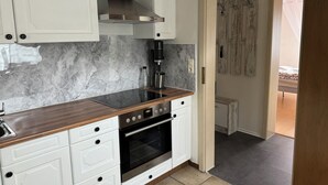 A modern kitchen with white cabinetry, a stainless steel range hood, a built-in oven, and a coffee maker. - Vacation apartment by the vineyards, great wine hiking trails nearby (Öhringen)
