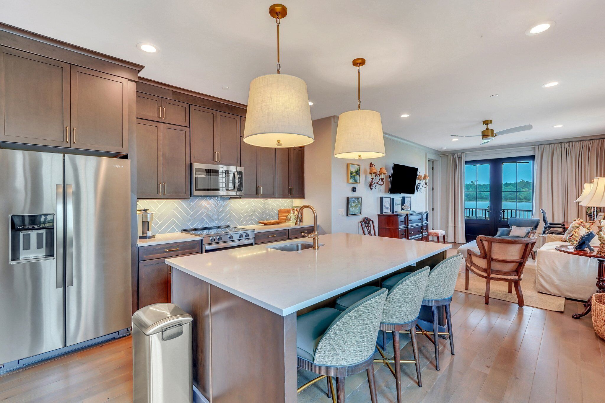 A modern kitchen with stainless steel appliances, a large island with bar stools, and pendant lighting.