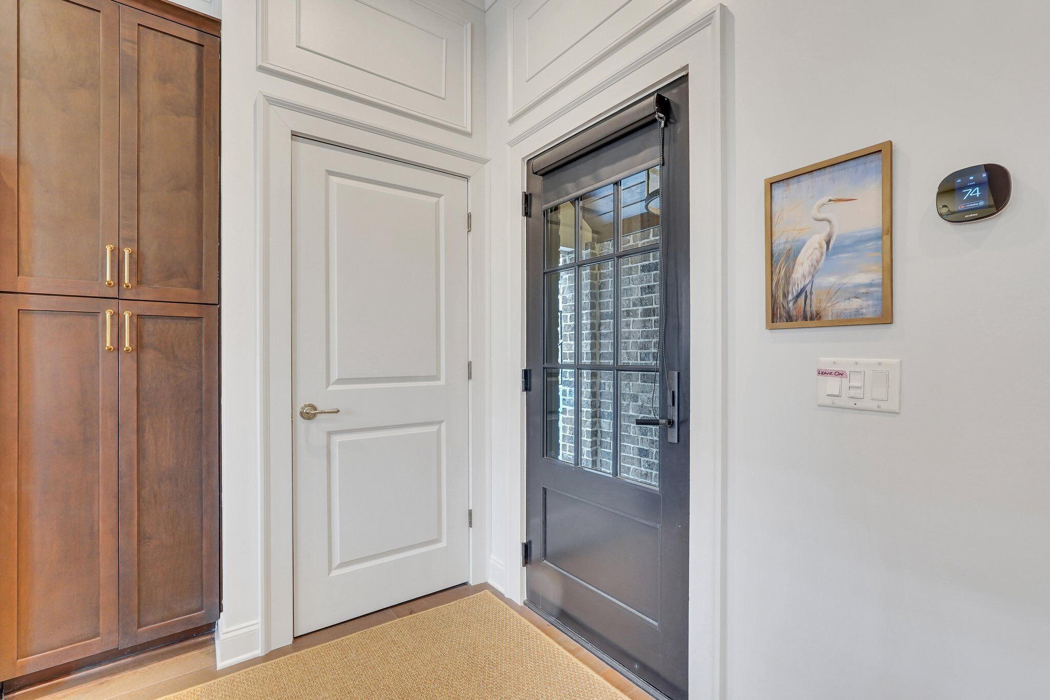 A door with a glass panel, a wooden cabinet, and a thermostat on the wall.