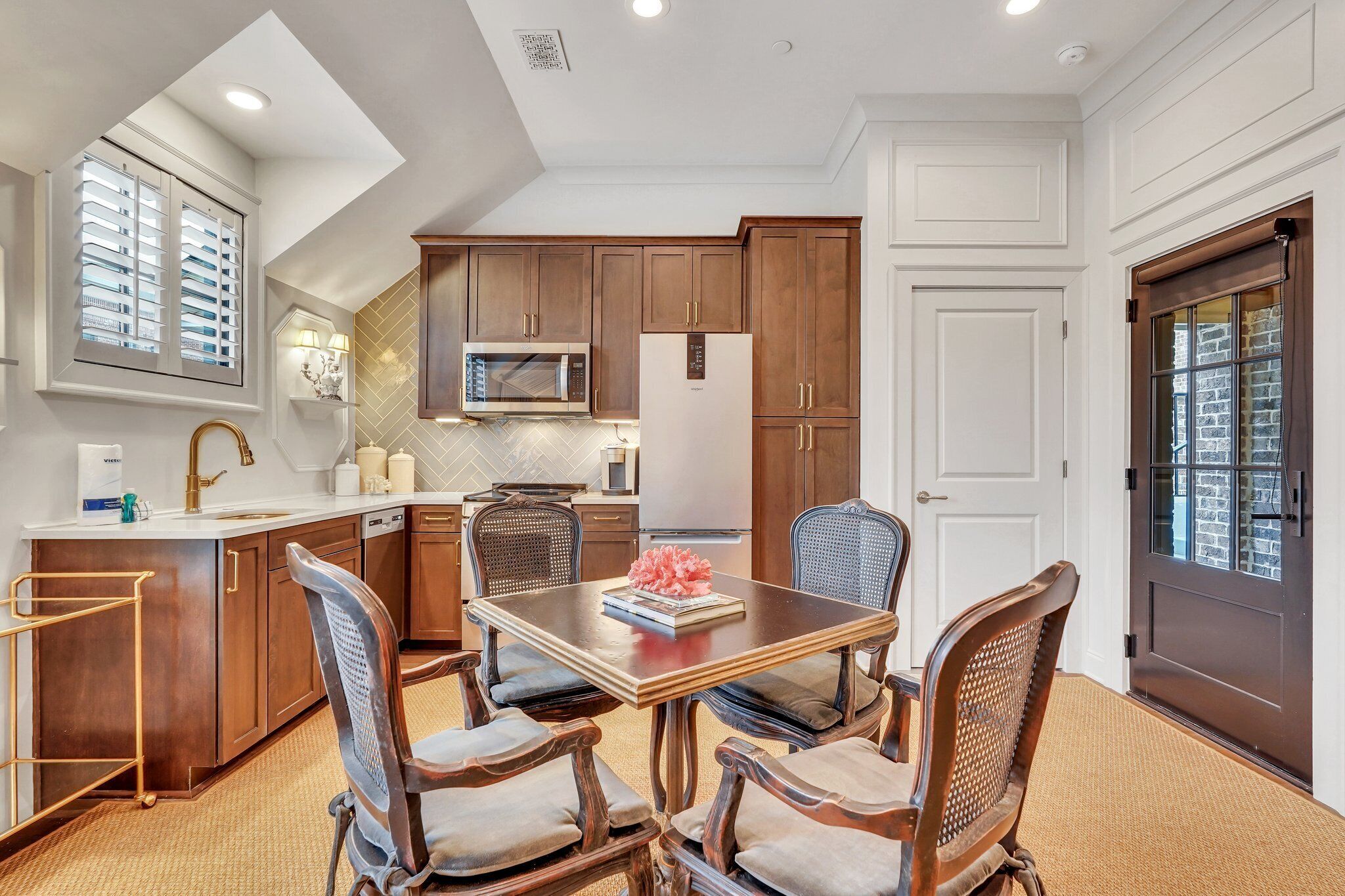 A modern kitchen with wooden cabinets, a central island, and a dining area with a table and chairs.