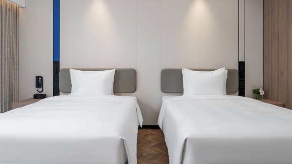 A hotel room with two beds, a phone on the nightstand, and a small plant on the nightstand.