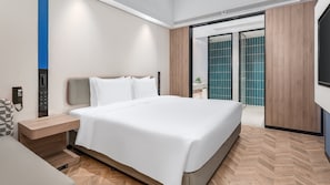 A modern hotel room with a large bed, a bedside table, a phone, and a view of the bathroom.