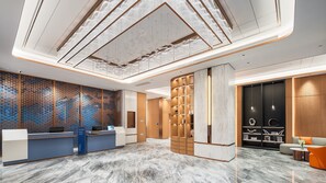 Un hall d’hôtel moderne comprenant un comptoir d’accueil, un espace salon et un plafond décoratif.