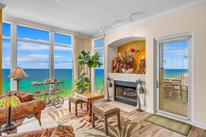 A spacious living room with a large window overlooking the ocean, a fireplace, and a cozy seating area.