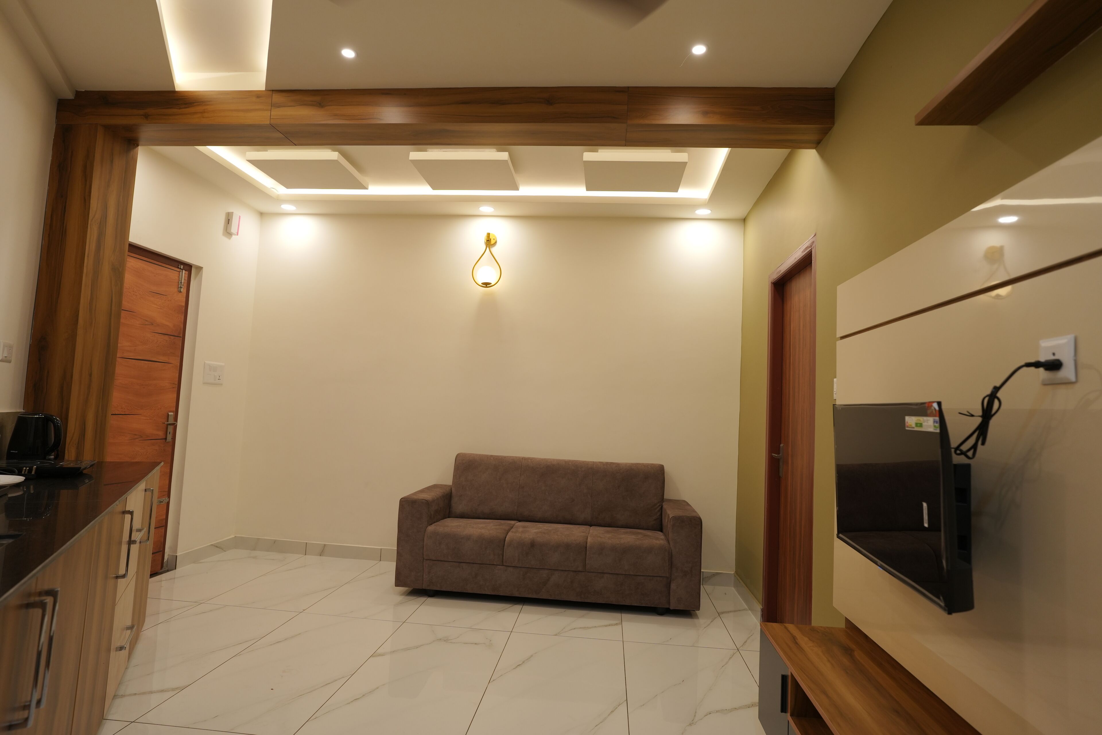 A modern living room with a sofa, a flat-screen TV, and a wooden ceiling.