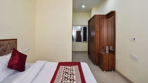 Una habitación de hotel con una cama, un armario de madera y un espejo.