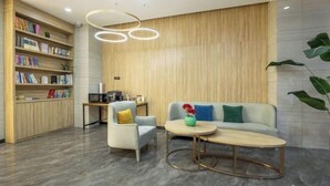 A modern reception area with a wooden reception desk, a sofa, a chair, and a coffee table. - Greentree Inn Express Deyang Changjiang Dong Road (Deyang)
