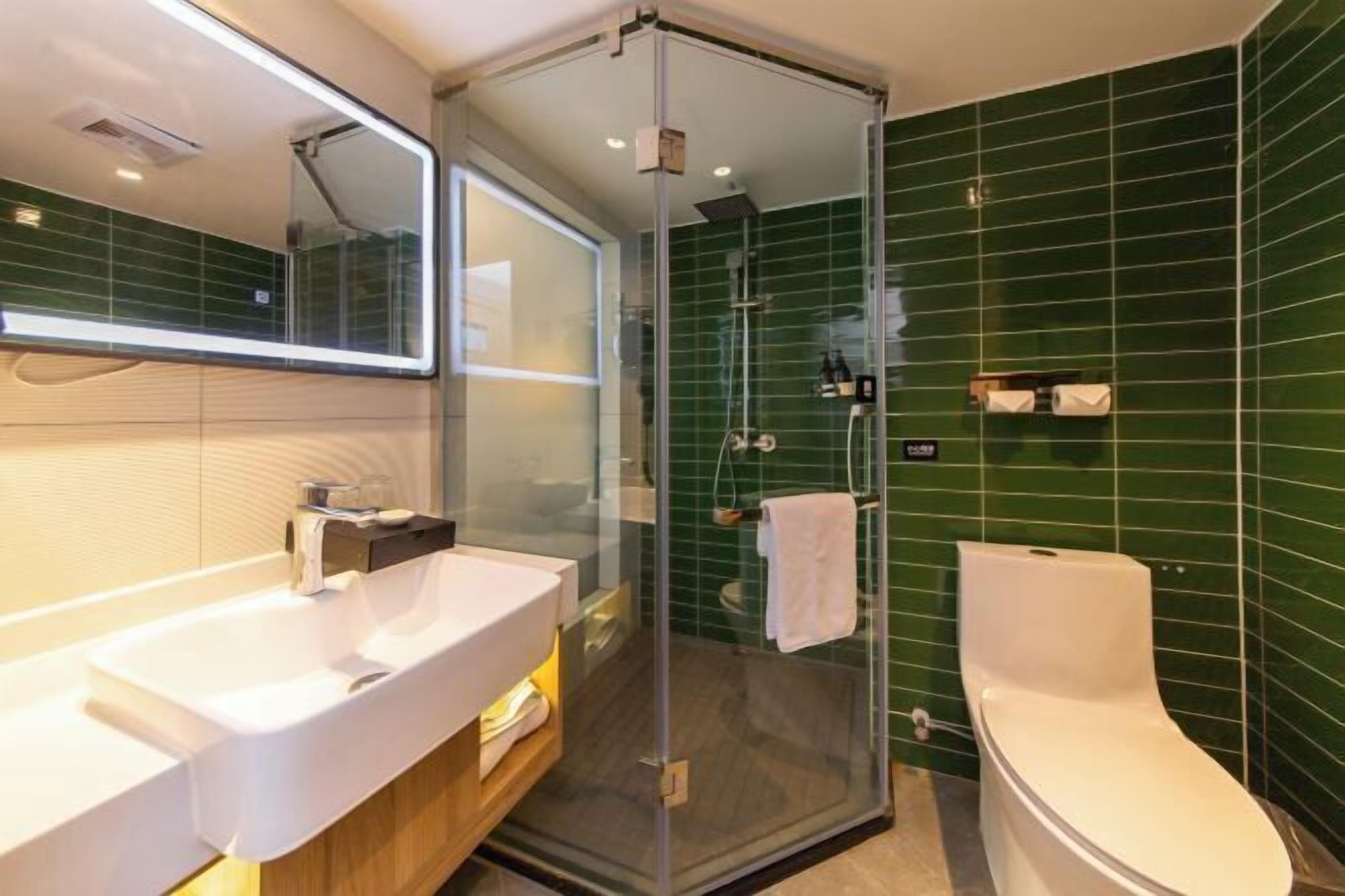 Een moderne badkamer met een douche met glazen wand, een witte wastafel en een toilet.