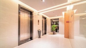 A modern hallway with elevators, a trash bin, and a potted plant. - Greentree Inn Express Deyang Changjiang Dong Road (Deyang)