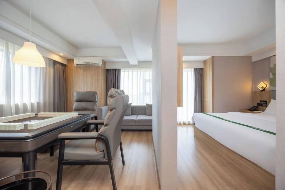 A modern hotel room with a dining area, a sofa, and a bed.