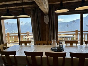 A wooden dining table with chairs, a candle holder, and curtains. - Chalet, 100m from ski slopes, hammam, terrace, fireplace or stove, tv, 210m², Les Saisies (Villard-sur-Doron)