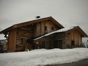 A rustic wooden cabin with a stone foundation, surrounded by snow. - Chalet, 100m from ski slopes, hammam, terrace, fireplace or stove, tv, 210m², Les Saisies (Villard-sur-Doron)