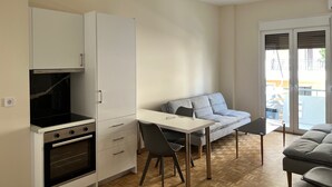 Een compacte keuken met een inbouwoven en een eethoek met tafel en stoelen.