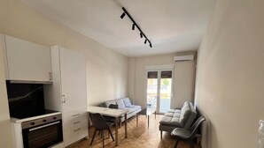 Een ruimtelijke leefruimte met een kitchenette, een eethoek en een zithoek.