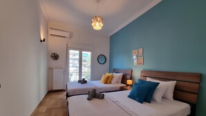 Een slaapkamer met twee bedden, een raam, een airconditioner en een wandklok.