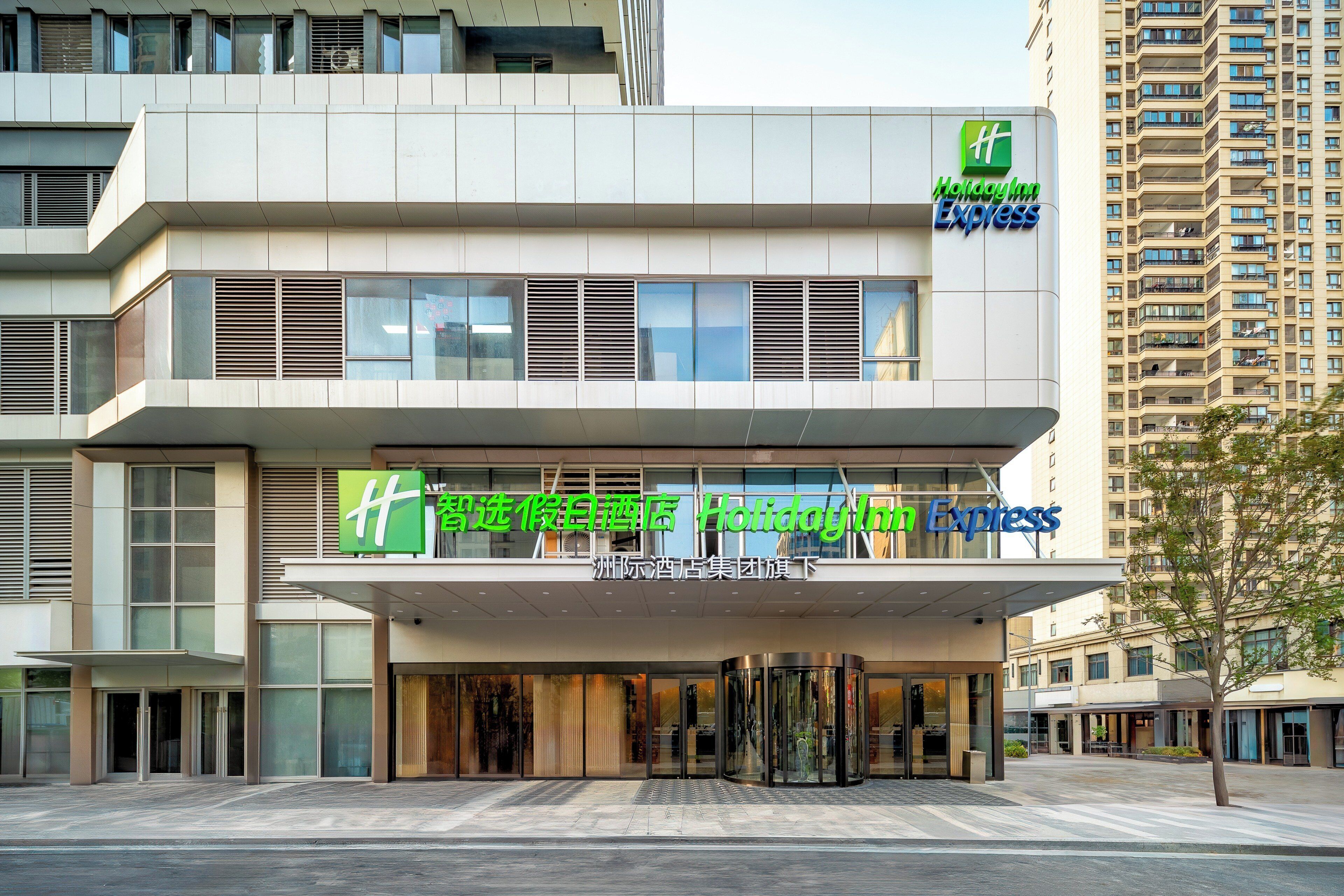 Un hotel Holiday Inn Express con una fachada moderna, amplias ventanas y una entrada destacada.