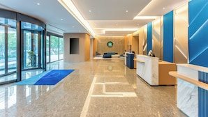 Een moderne hotellobby met een receptiebalie, een zithoek en grote ramen met uitzicht op het landschap.