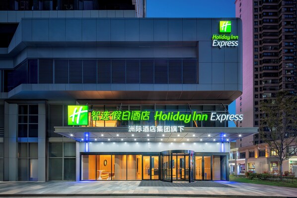 Entrada de un hotel Holiday Inn Express con un diseño moderno, que presenta un letrero destacado y una puerta de vidrio.