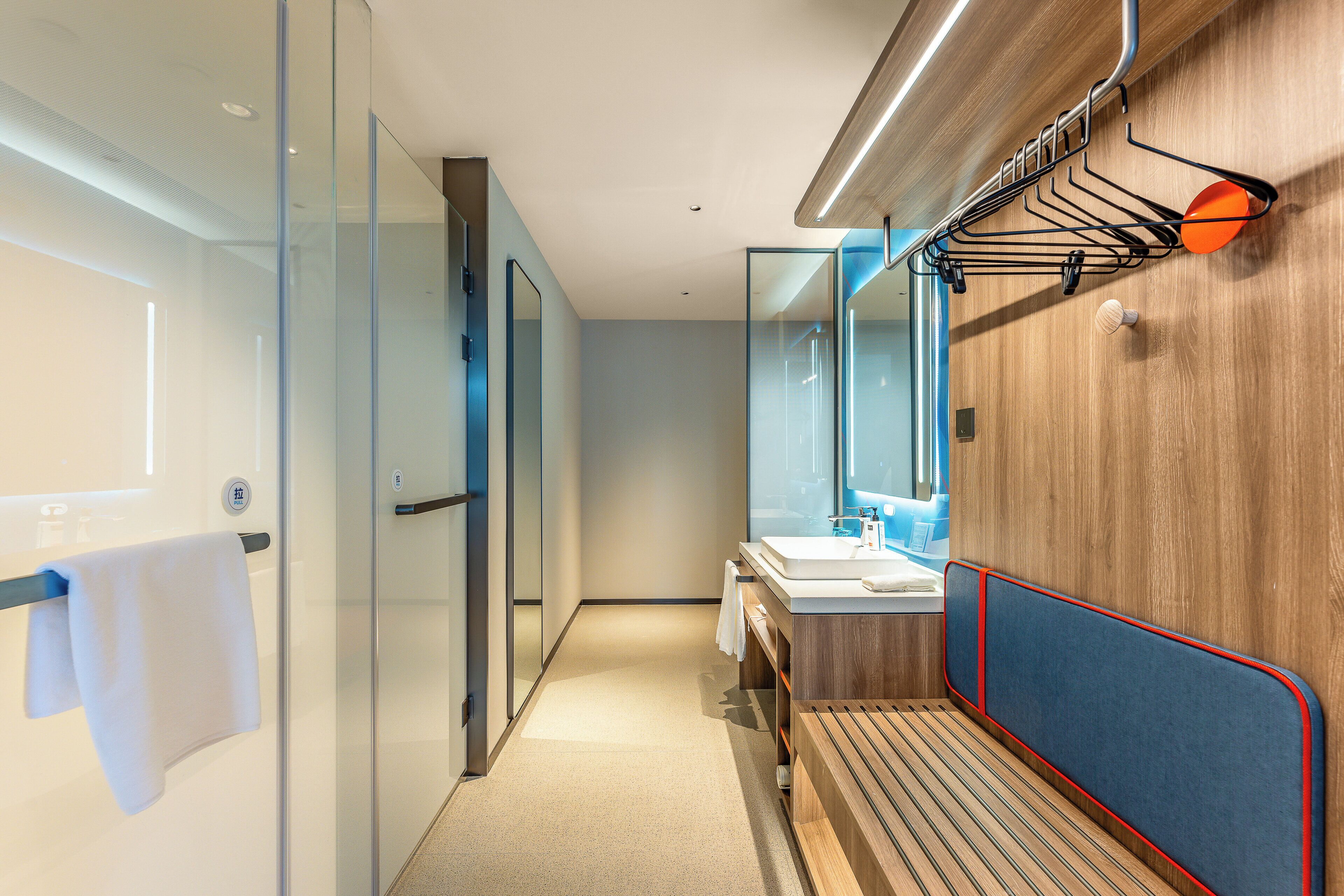 Une salle de bain moderne avec une douche à parois de verre, un meuble-lavabo en bois avec un miroir et un porte-serviettes.