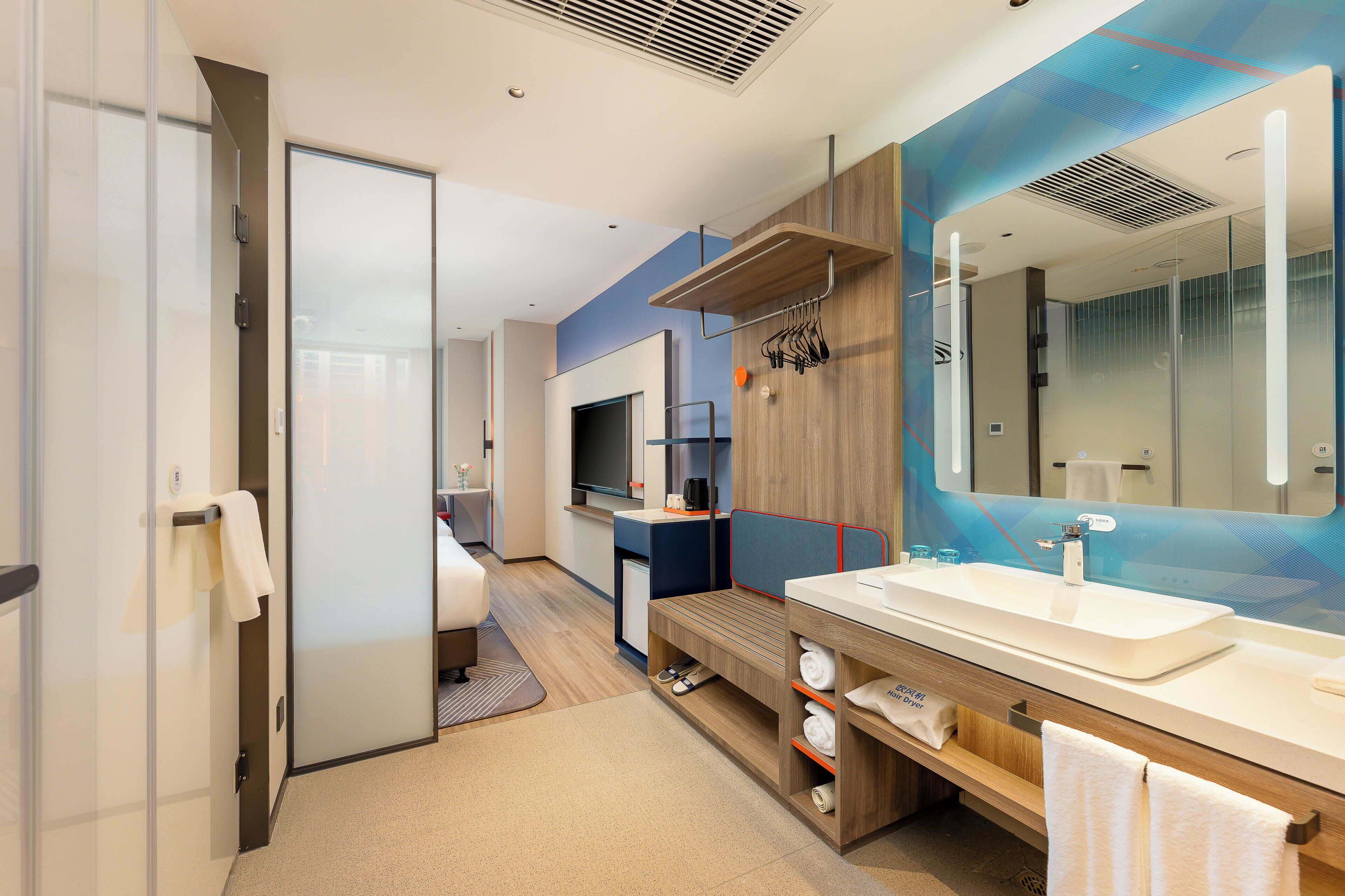 Un baño de hotel moderno con un espejo grande, un lavamanos y una zona de ducha.
