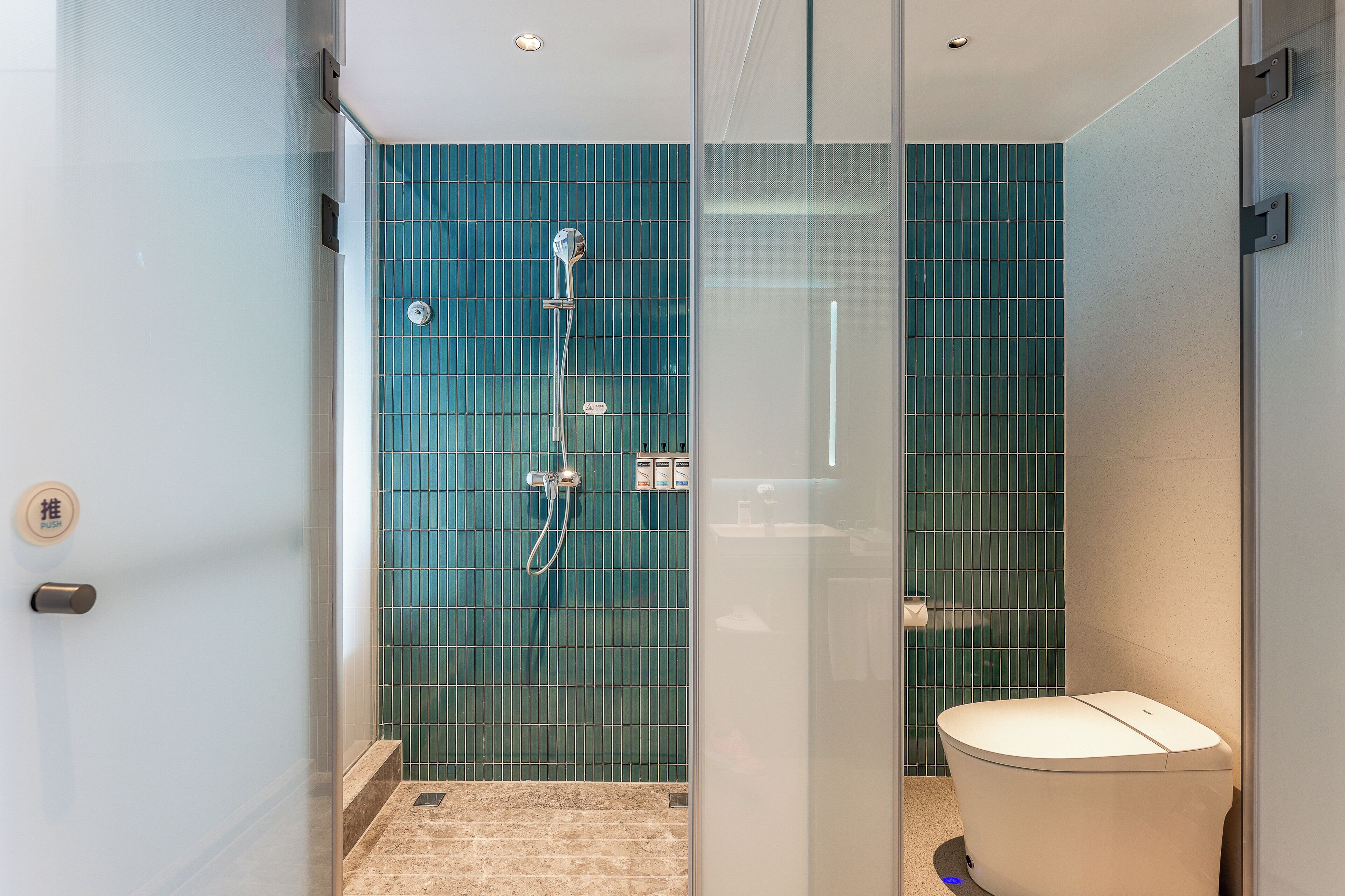 Un bagno moderno con box doccia in vetro, un water e una parete rivestita di piastrelle.