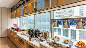 Een moderne keukenruimte met een buffetopstelling, inclusief diverse gerechten en keukenapparatuur.