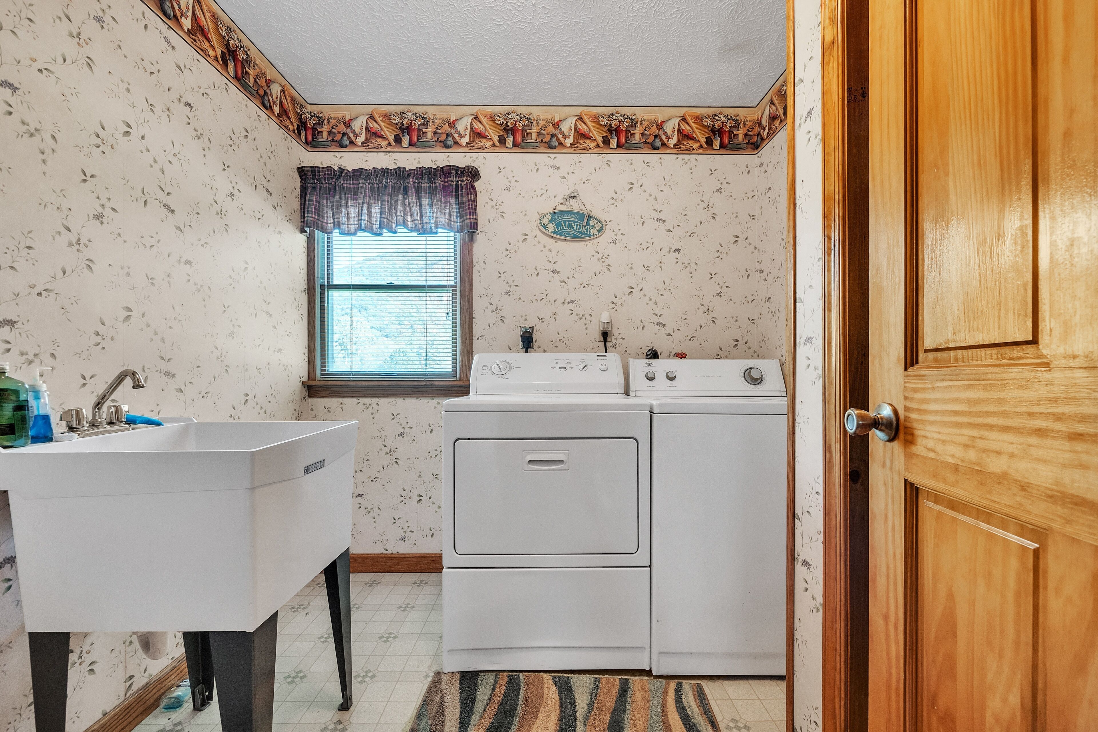 A small laundry room with a white sink, a washing machine, and a dryer.