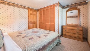 A bedroom with a bed, a wooden dresser, a mirror, and a closet.