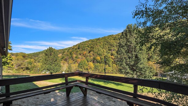 A wooden deck with a picnic table and benches overlooking a grassy area with trees and a hill. - Bear Paw Cottage- 12 Mins To Seneca Rocks 3 Bedroom Cottage (Seneca Rocks)
