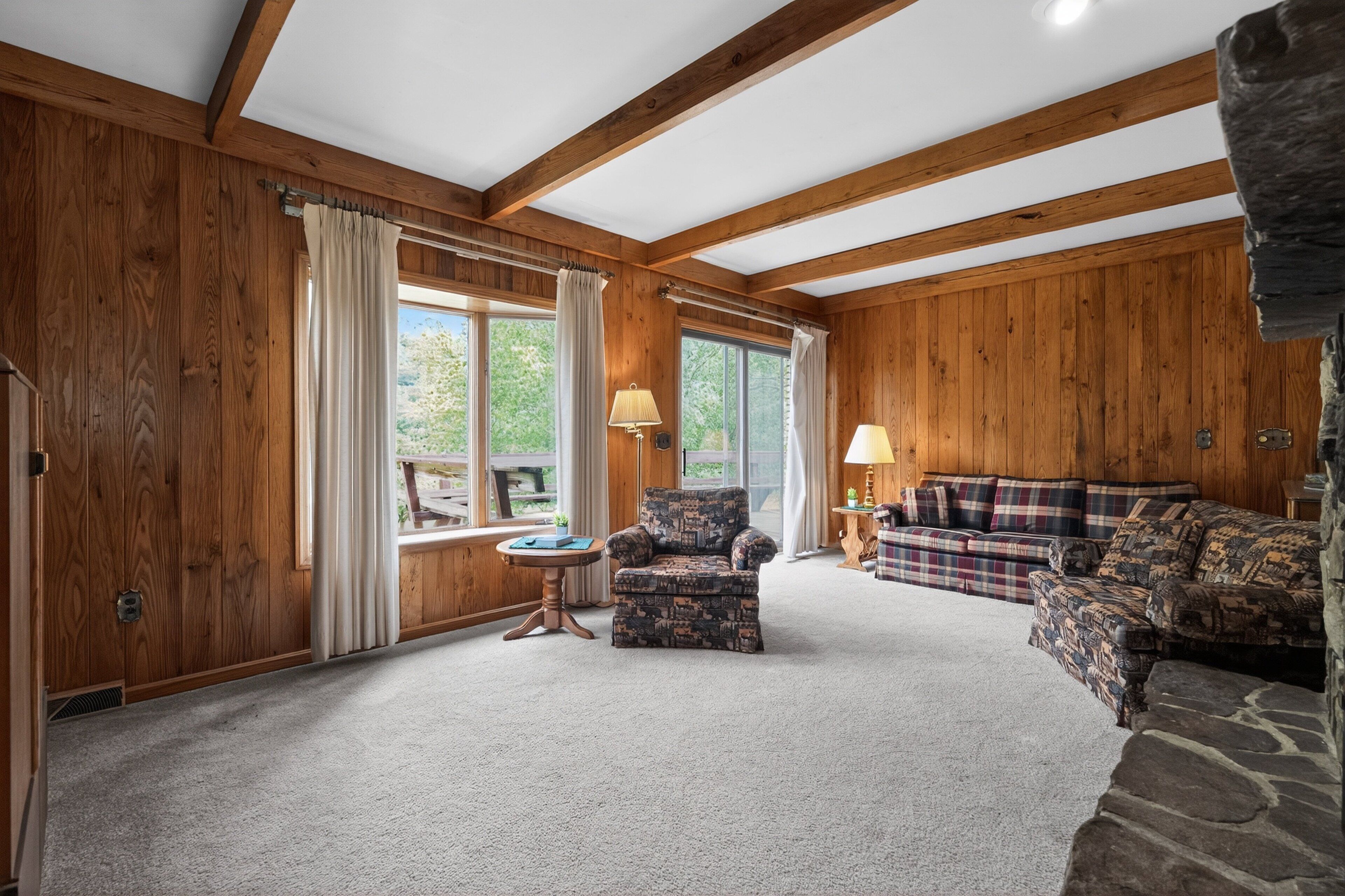 A wooden-paneled room with a sofa, armchair, and a small table.