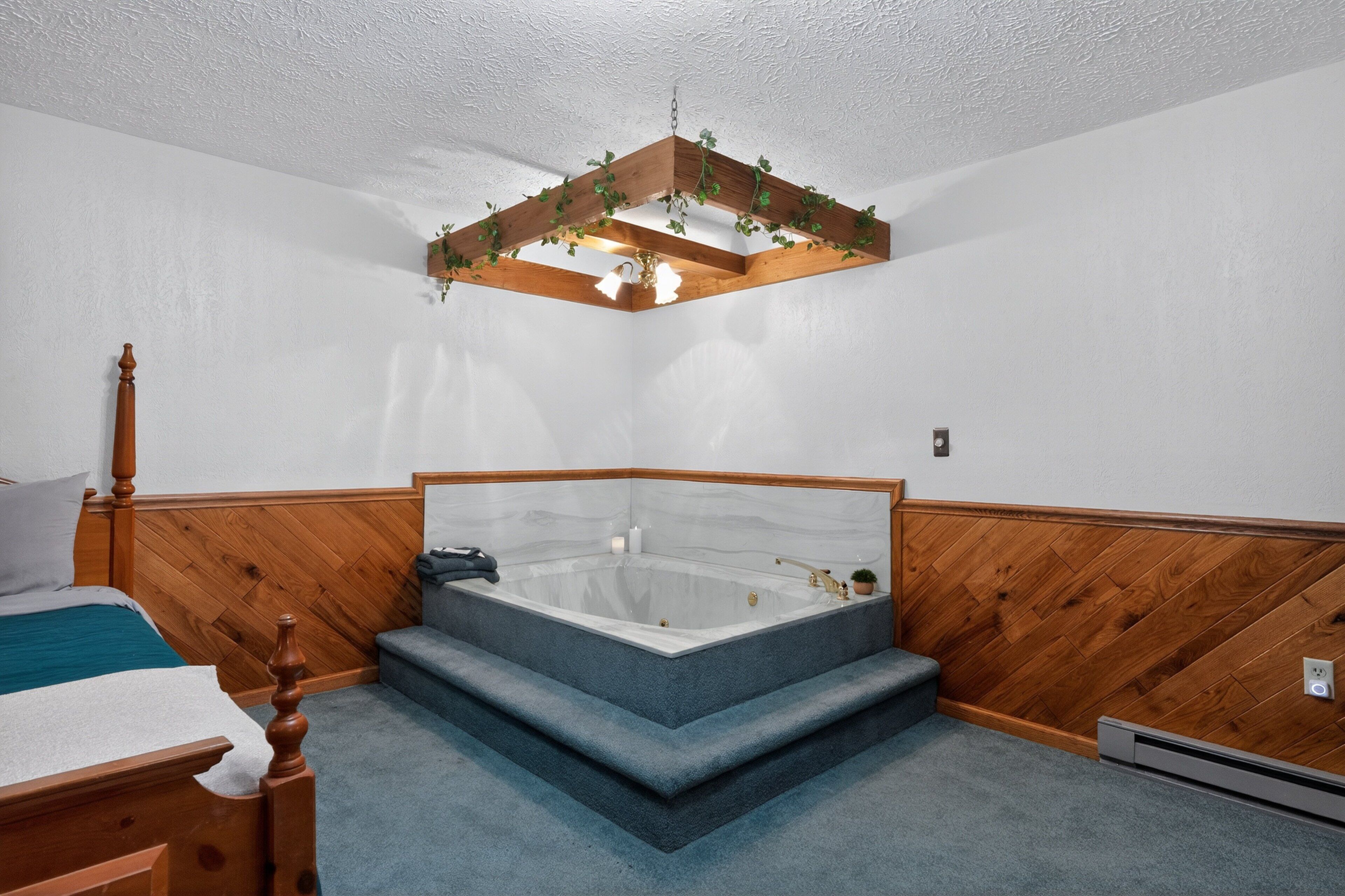 Un dormitorio con cabecera de madera, una bañera grande y un techo de madera con plantas colgantes.