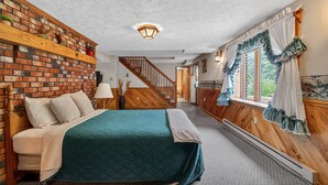 A bedroom with a brick wall, wooden staircase, and a bed with a quilted bedspread. - Bear Paw Cottage- 12 Mins To Seneca Rocks 3 Bedroom Cottage (Seneca Rocks)