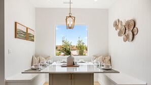 Een moderne keuken met een centraal eiland, witte kasten en een groot raam met uitzicht op een woestijnlandschap.