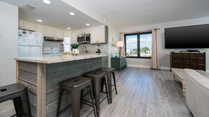 Una cocina moderna con una isla central, taburetes de bar y un amplio ventanal con vistas.