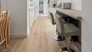 Uma cozinha moderna com armários brancos, micro-ondas e máquina de café.