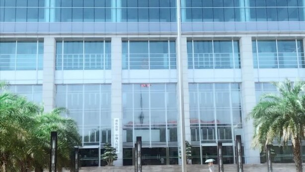 Een modern gebouw met grote glasramen en een vlaggenmast op het dak.