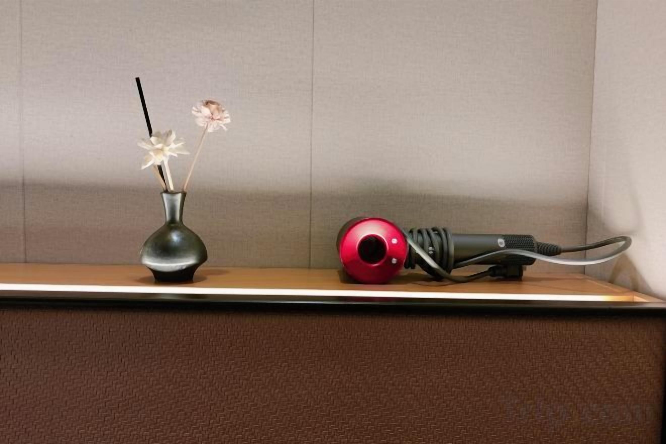 Une étagère avec un vase et un sèche-cheveux.