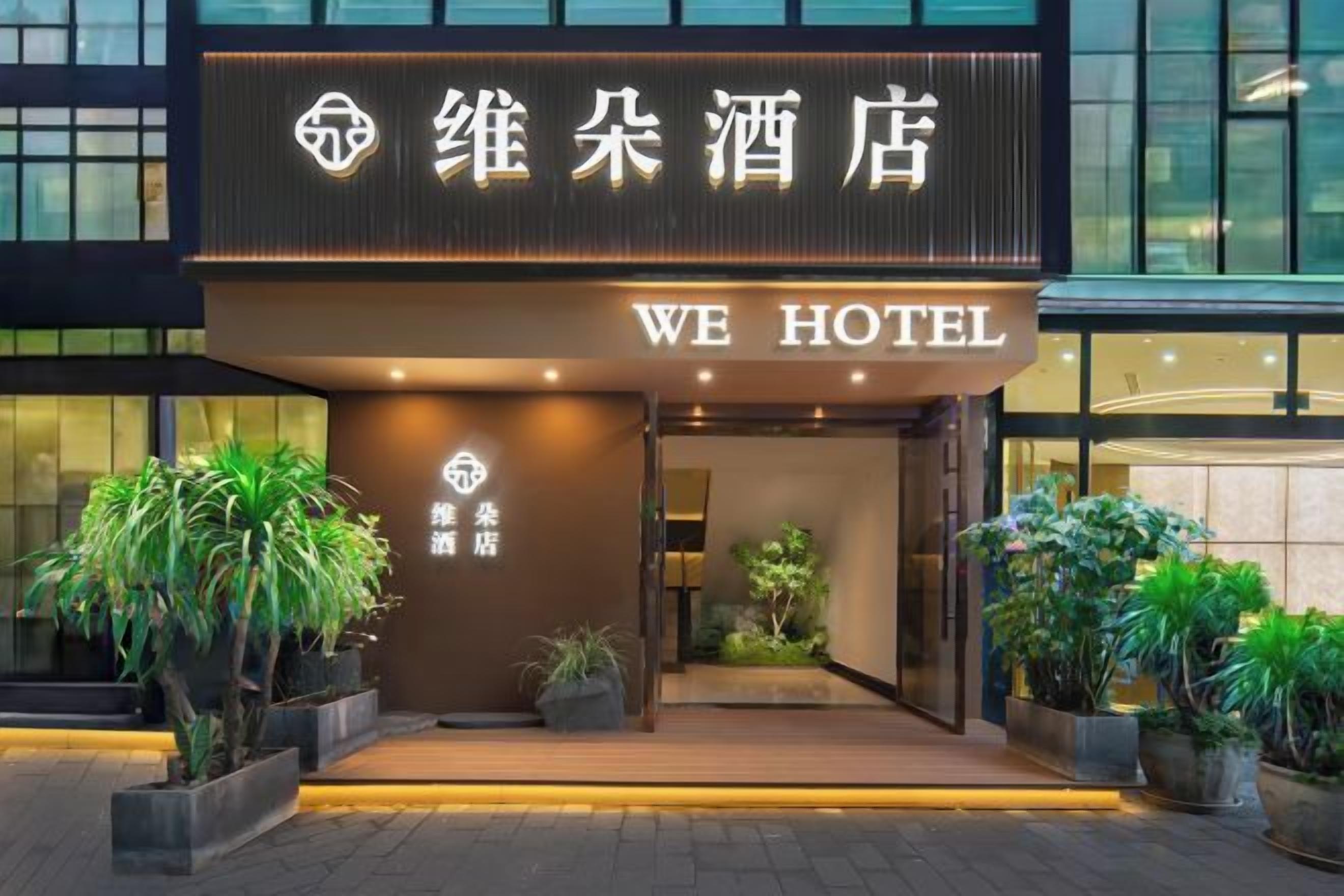 Ein Hotel Eingang mit einem Schild, auf dem 'WE HOTEL' und chinesische Schriftzeichen stehen.