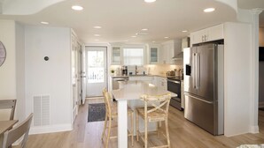 A modern kitchen with white cabinetry, a central island, and a stainless steel refrigerator.