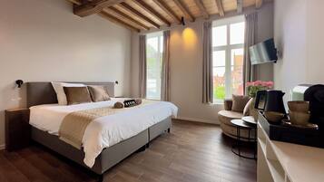 Une chambre à coucher avec un lit, un bureau avec une chaise, une télévision et une fenêtre avec des rideaux.
