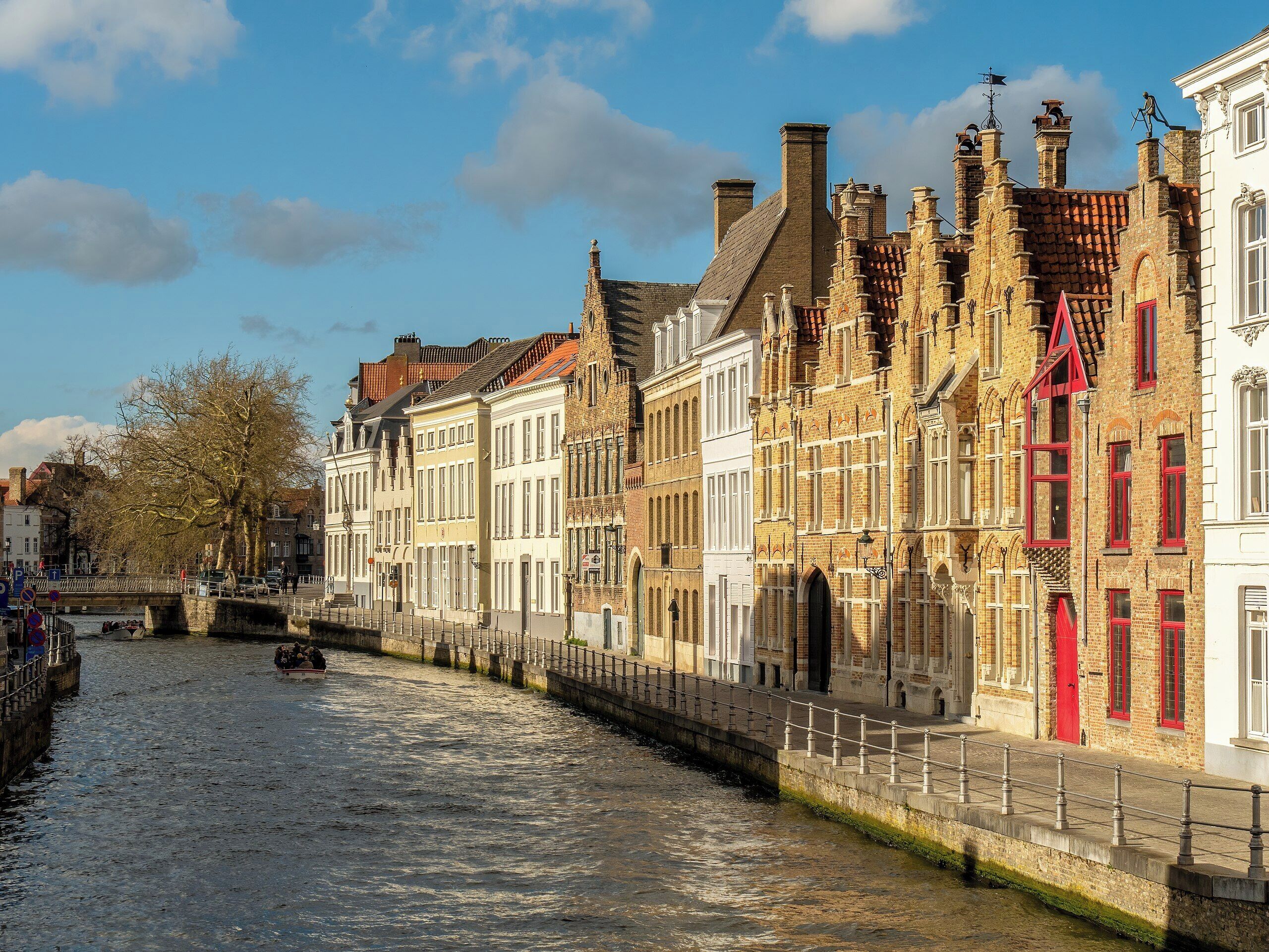 A canal with historic buildings on one side and a bridge in the background.
